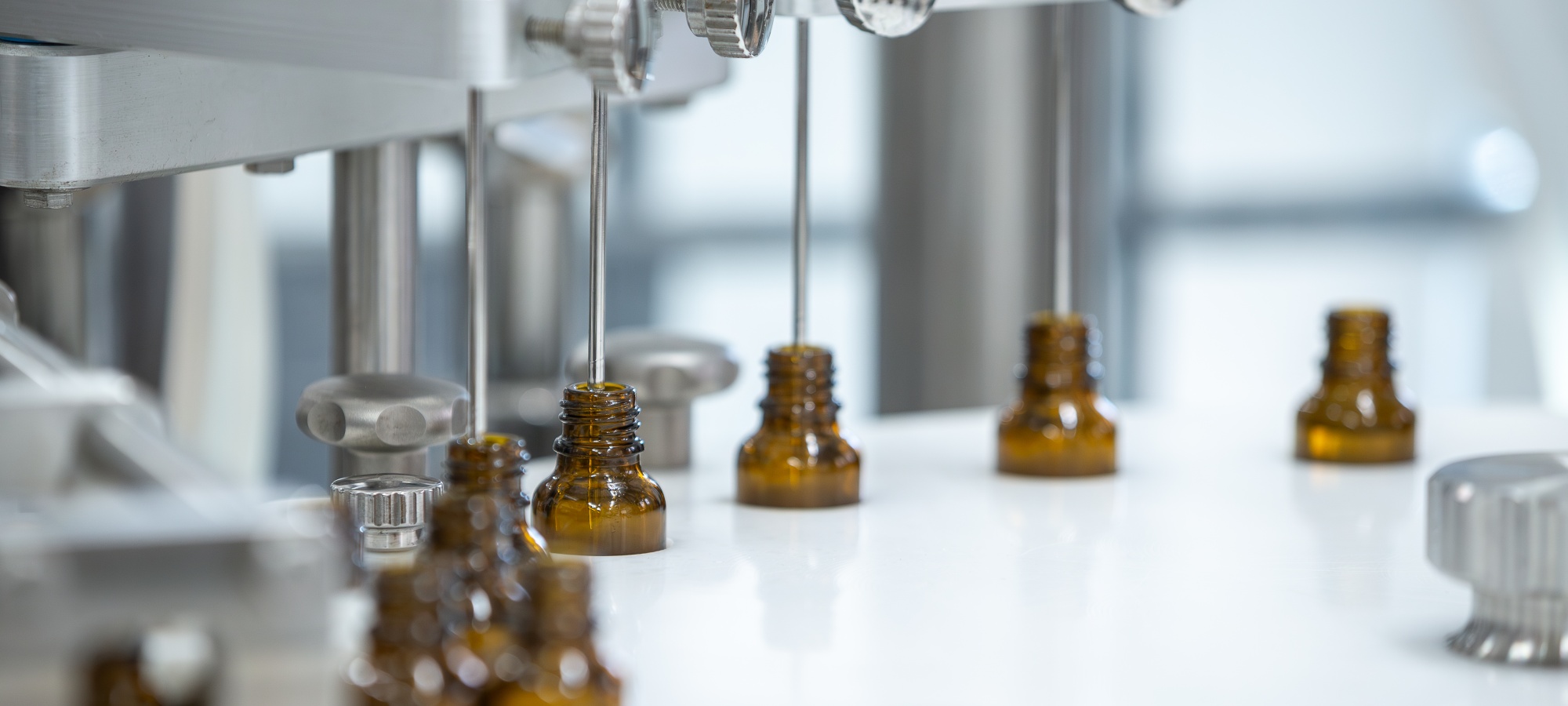 mehrere 10ml Braunglasflaschen die maschinell bef&uuml;llt werden