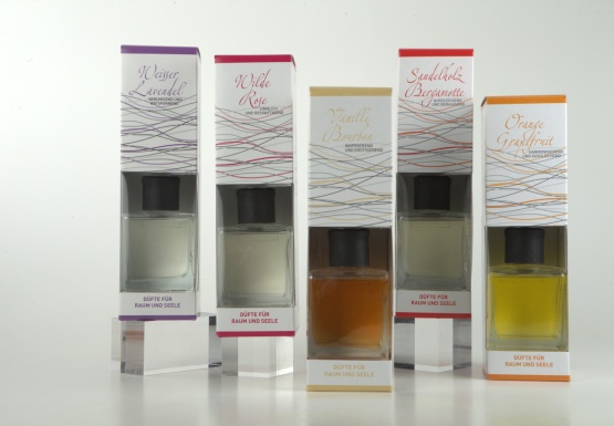 Nebeneinander aufgereihte 5 Sorten Raumd&uuml;fte in 4eck Flasche mit schwarzer Kunststoffkappe in wei&szlig;er Verpackung mit Sichtfenster auf die Flaschen