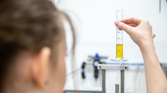 Eine Person f&uuml;hrt eine Kontrolle durch, sie h&auml;lt ein Reagenzglas in der Hand und kontrolliert die F&uuml;llmenge und Konzentration